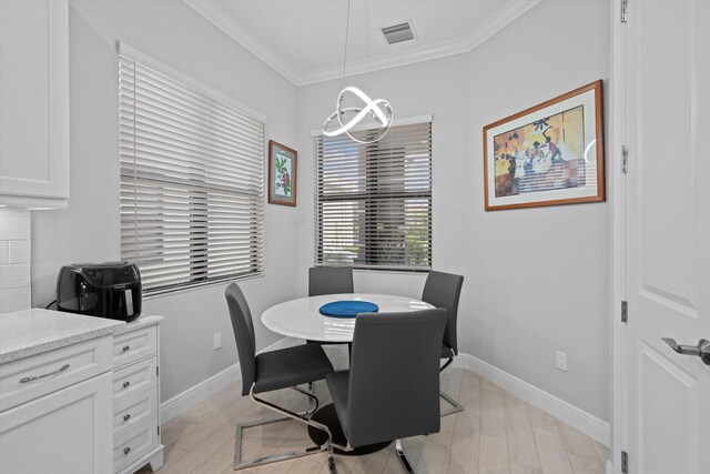 dining space with ornamental molding and light hardwood / wood-style floors