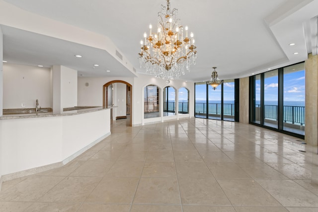 interior space featuring sink, light tile patterned floors, expansive windows, a chandelier, and a water view