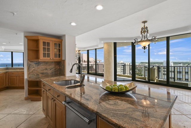 kitchen with decorative backsplash, a wealth of natural light, sink, and an island with sink