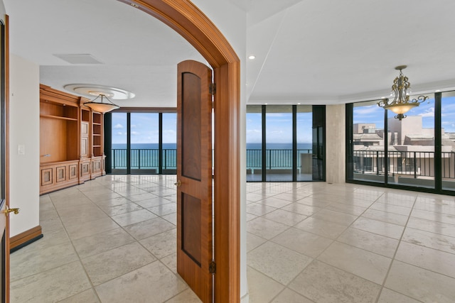 hall with a water view, a wall of windows, and a chandelier