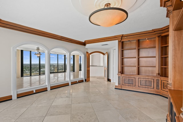 tiled empty room featuring a notable chandelier and ornamental molding