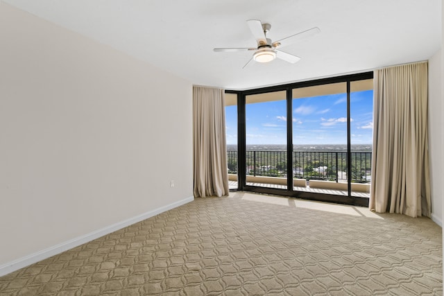 carpeted spare room featuring expansive windows and ceiling fan