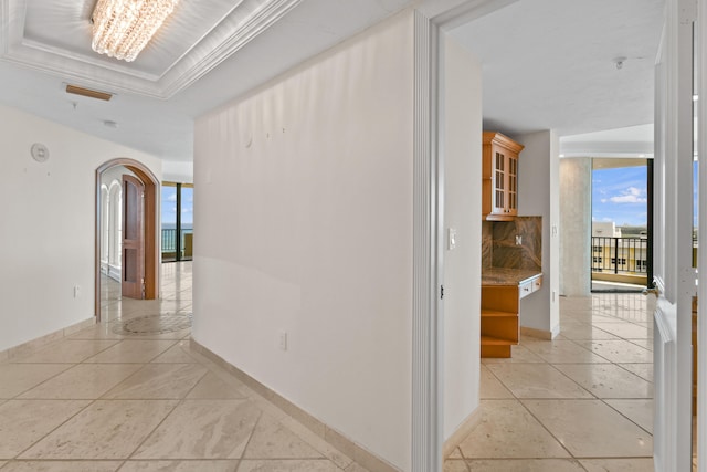 corridor with a notable chandelier and ornamental molding