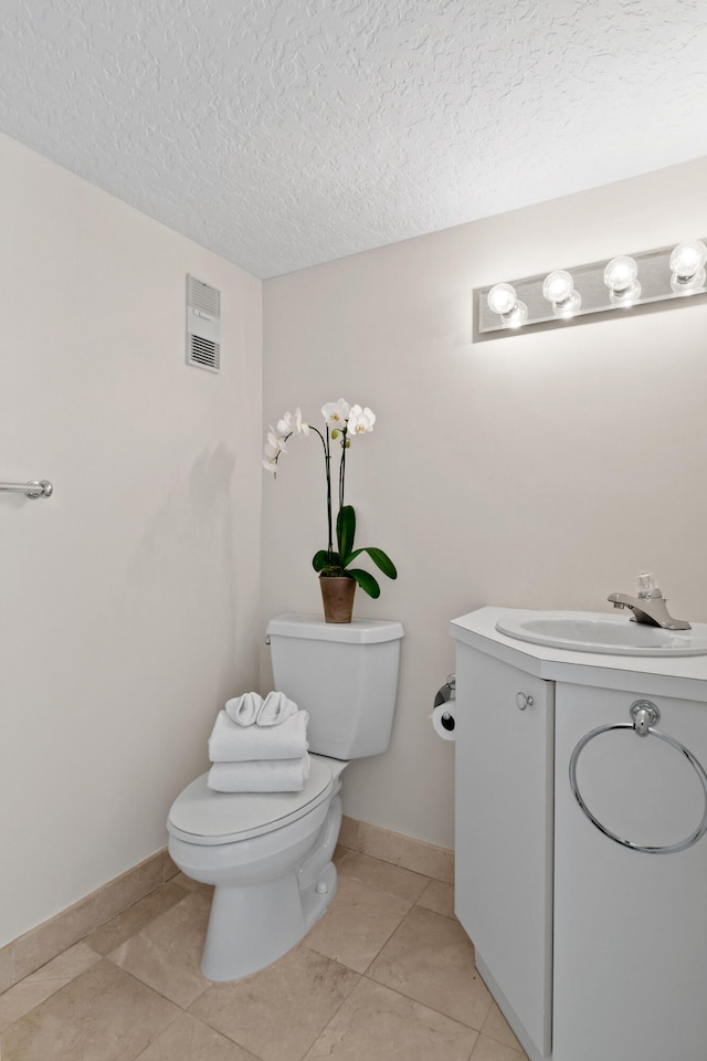 bathroom with tile patterned flooring, vanity, toilet, and a textured ceiling