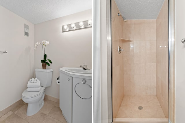 bathroom with vanity, tile patterned floors, toilet, tiled shower, and a textured ceiling