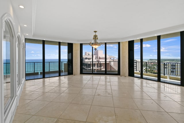 tiled empty room with a chandelier, a water view, and floor to ceiling windows