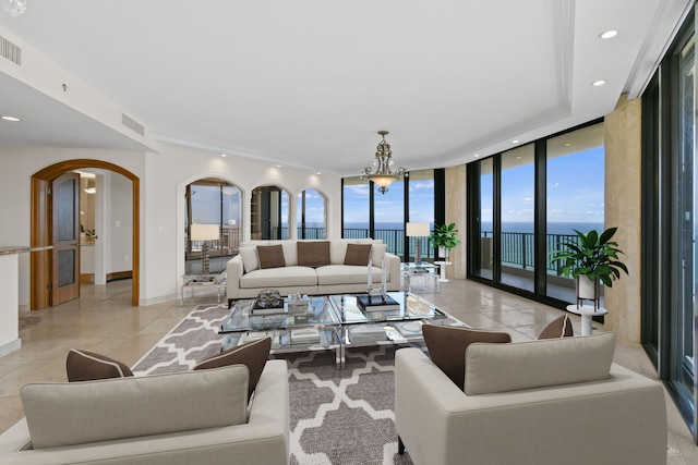 living room with expansive windows, a water view, and a notable chandelier