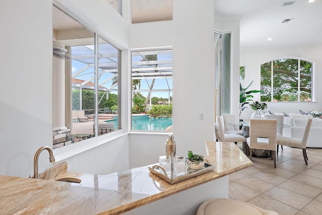 dining space featuring sink, light tile patterned floors, ornamental molding, and a wealth of natural light