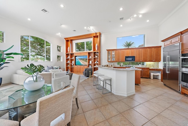 kitchen featuring ornamental molding, a kitchen breakfast bar, appliances with stainless steel finishes, and backsplash