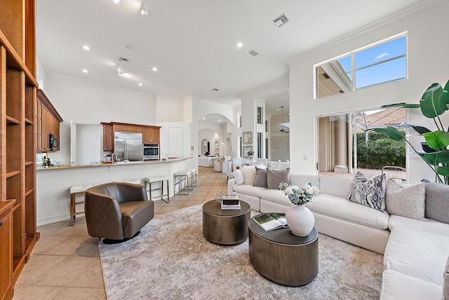 tiled living room with ornamental molding and a towering ceiling