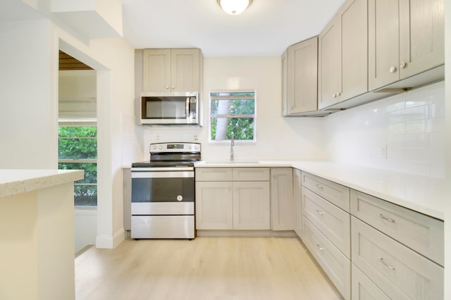 kitchen with light hardwood / wood-style floors, decorative backsplash, sink, and stainless steel appliances