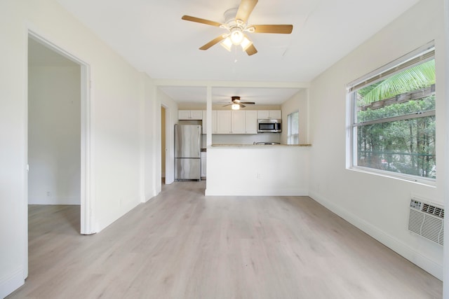 unfurnished living room with a wall unit AC, ceiling fan, and light hardwood / wood-style floors