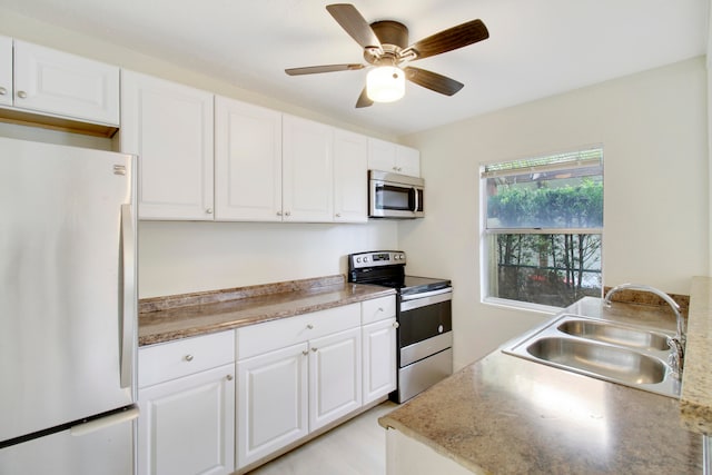 kitchen featuring appliances with stainless steel finishes, ceiling fan, white cabinetry, and sink