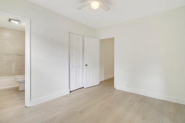 unfurnished bedroom featuring a closet, ensuite bathroom, light wood-type flooring, and ceiling fan