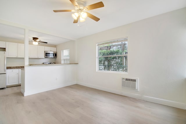 interior space featuring ceiling fan, light hardwood / wood-style floors, and heating unit