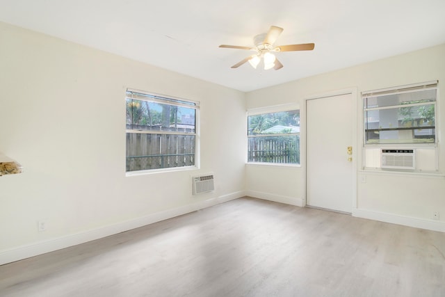 unfurnished room with a wall mounted AC, light hardwood / wood-style flooring, and ceiling fan