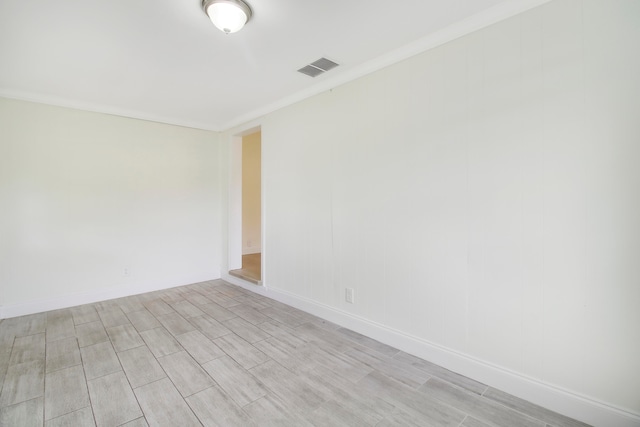 empty room featuring ornamental molding and light wood-type flooring