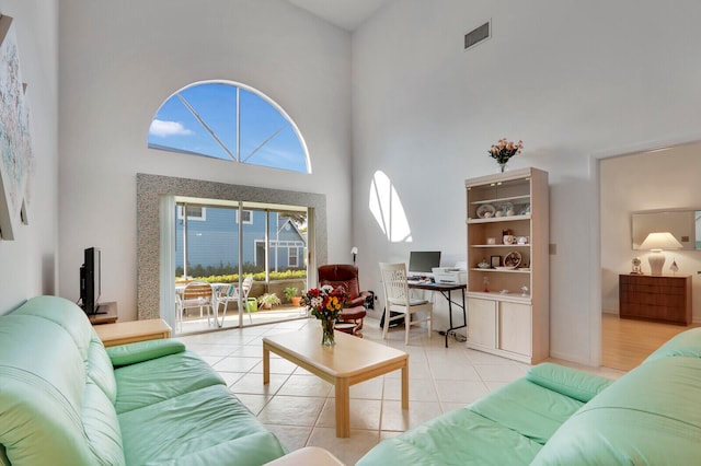 living room with a towering ceiling and light tile patterned floors