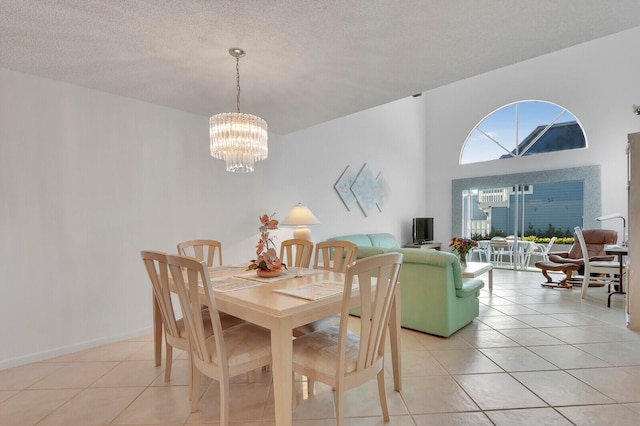 dining room with a chandelier, light tile patterned flooring, a textured ceiling, and a high ceiling