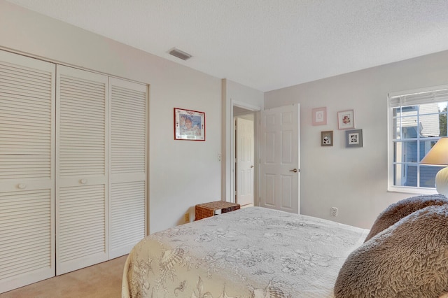 bedroom featuring light carpet, a closet, and a textured ceiling