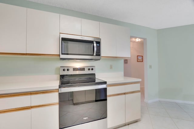 kitchen featuring a textured ceiling, white cabinets, stainless steel appliances, and light tile patterned floors