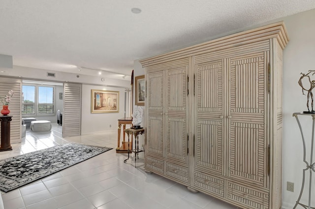 hallway featuring a textured ceiling and light tile patterned floors