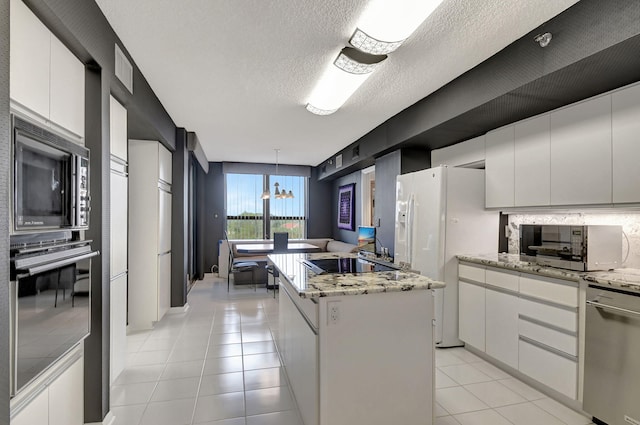 kitchen featuring stainless steel appliances, white cabinetry, a textured ceiling, decorative light fixtures, and a kitchen island