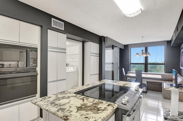 kitchen featuring white cabinetry, black appliances, a textured ceiling, washer / dryer, and a notable chandelier