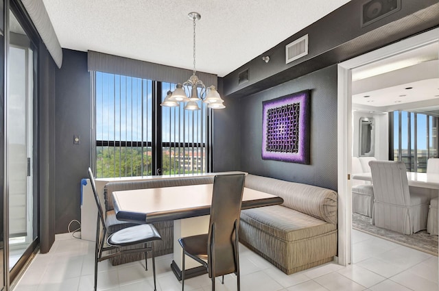 tiled dining space featuring breakfast area, a textured ceiling, and an inviting chandelier