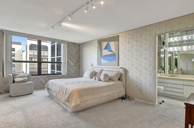 carpeted bedroom featuring rail lighting, a textured ceiling, and connected bathroom