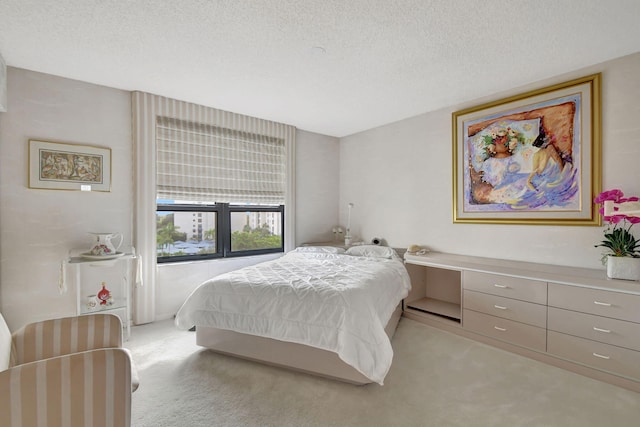 bedroom with built in desk, a textured ceiling, and light colored carpet