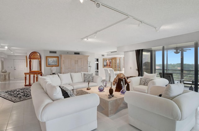 tiled living room featuring track lighting, ceiling fan, and a textured ceiling