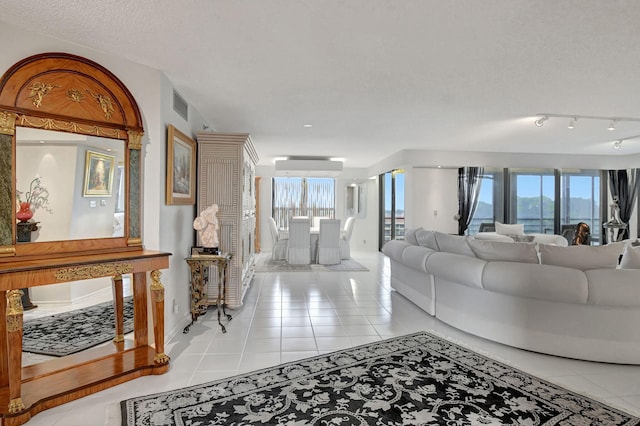 tiled living room with a wealth of natural light, a textured ceiling, and a wall unit AC