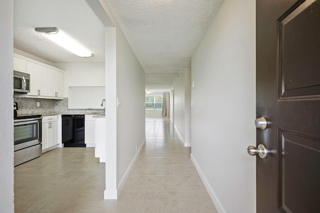 hall with sink, light tile patterned floors, and a textured ceiling