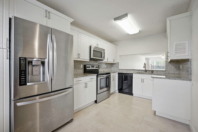 kitchen with appliances with stainless steel finishes, light stone countertops, sink, and white cabinets