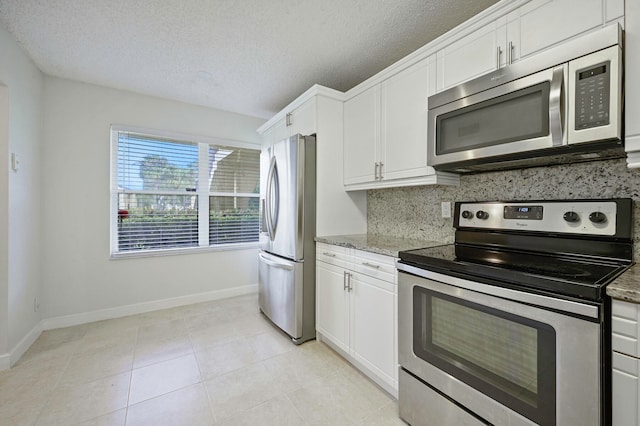 kitchen featuring appliances with stainless steel finishes, light stone counters, white cabinetry, and a textured ceiling