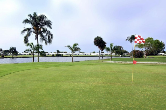 surrounding community with a lawn, a water view, and golf course view
