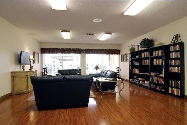 living room with a textured ceiling, baseboards, and wood finished floors