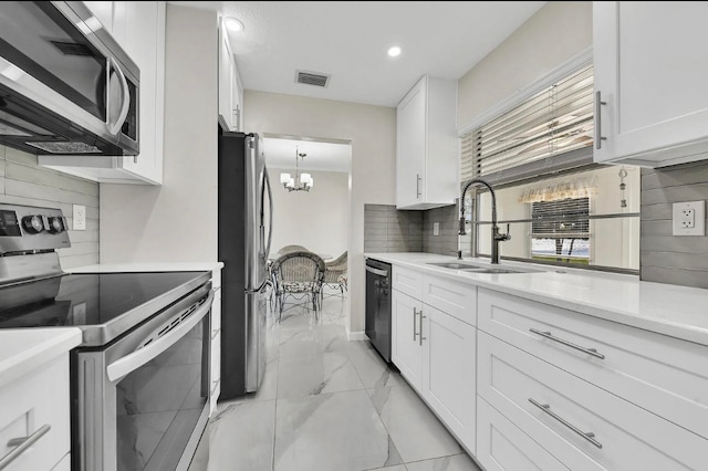 kitchen featuring an inviting chandelier, sink, stainless steel appliances, and white cabinets