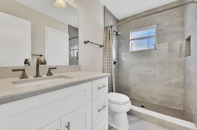 full bath with vanity, a tile shower, and toilet
