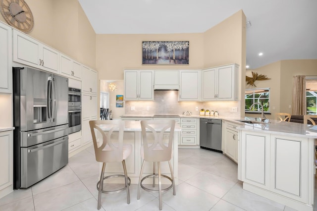 kitchen featuring white cabinets, sink, stainless steel appliances, a center island, and a breakfast bar area