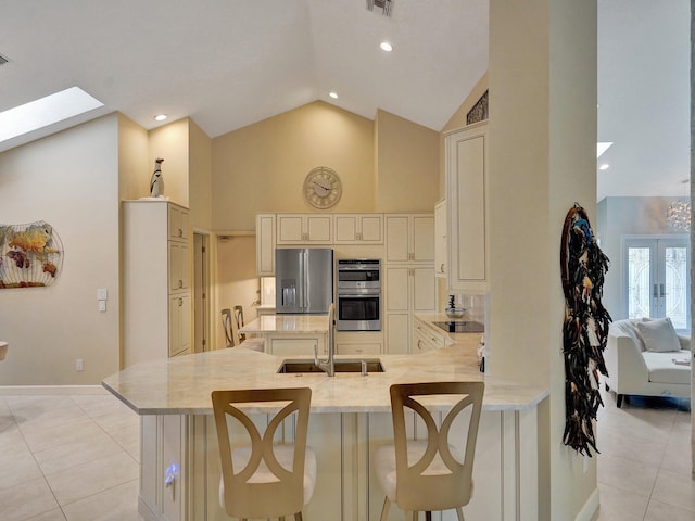 kitchen featuring stainless steel appliances, sink, kitchen peninsula, a skylight, and a kitchen breakfast bar