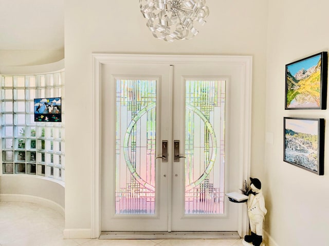 entryway featuring a notable chandelier, french doors, and light tile patterned floors