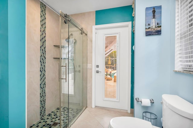 bathroom featuring toilet, an enclosed shower, and tile patterned floors