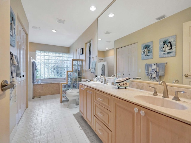 bathroom featuring a relaxing tiled tub, vanity, toilet, and tile patterned floors