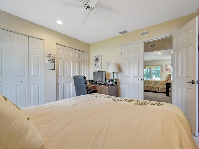 carpeted bedroom with ceiling fan and multiple closets