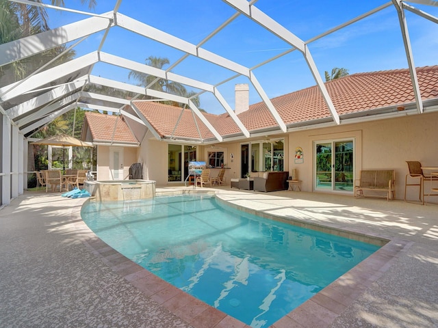 rear view of house with a pool with hot tub, a lanai, and a patio area