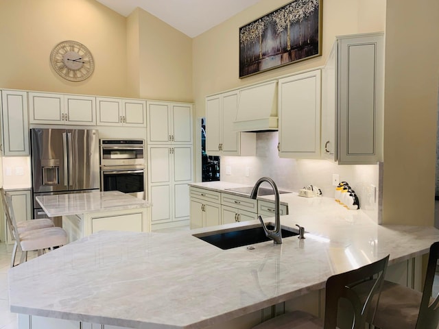 kitchen featuring light stone counters, sink, kitchen peninsula, stainless steel appliances, and a breakfast bar