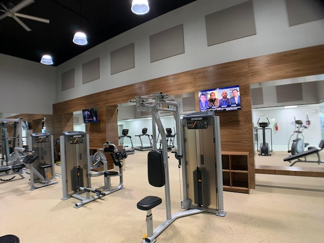 gym with a high ceiling, wooden walls, and carpet floors