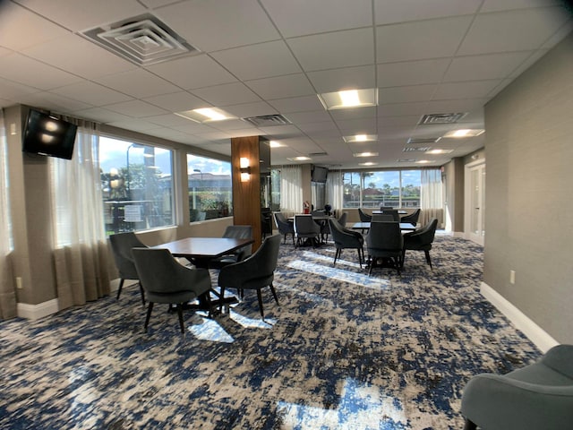 carpeted dining room featuring a paneled ceiling and a healthy amount of sunlight